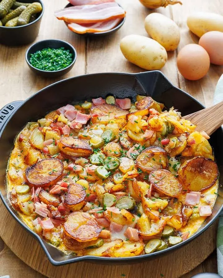 Deftiges Bauernfrühstück mit Eiern, Speck und frischen Zutaten auf dem Teller.