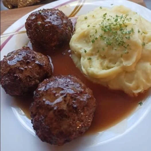 Frikadellen mit Kartoffelbrei und Soße auf einem Teller serviert