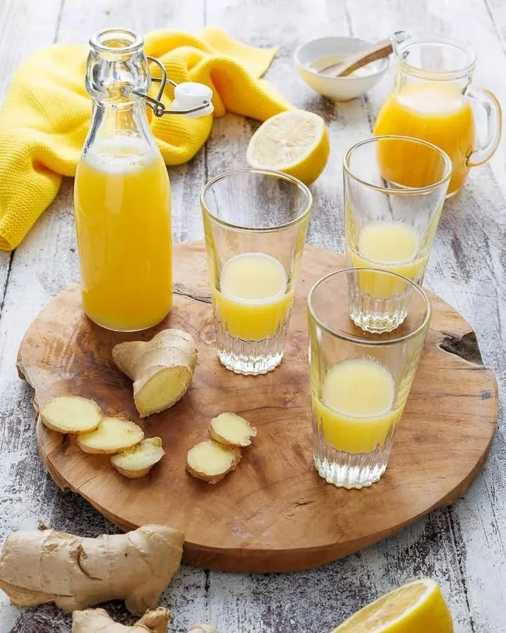 Hausgemachter Ingwer-Shot in einem Glas mit frischem Ingwer und Zitrone