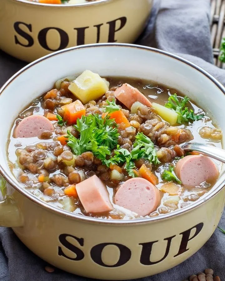 Eine Schüssel klassischen Linseneintopf mit frischen Kräutern garniert.