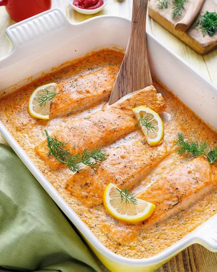 Lachs-Sahne-Gratin in einer weißen Auflaufform mit frischen Kräutern garniert