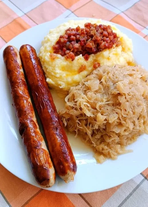 Thüringer Bratwurst serviert mit Kartoffelpüree und Sauerkraut auf einem Teller