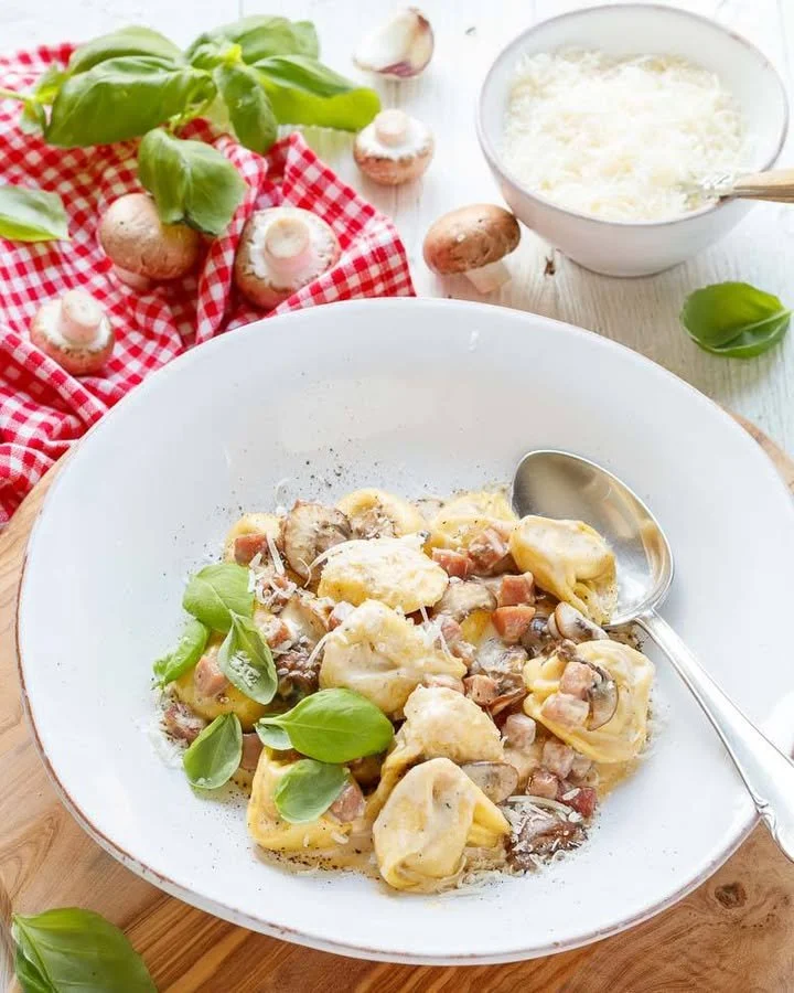 Tortellini mit Sahnesauce auf einem Teller angerichtet.