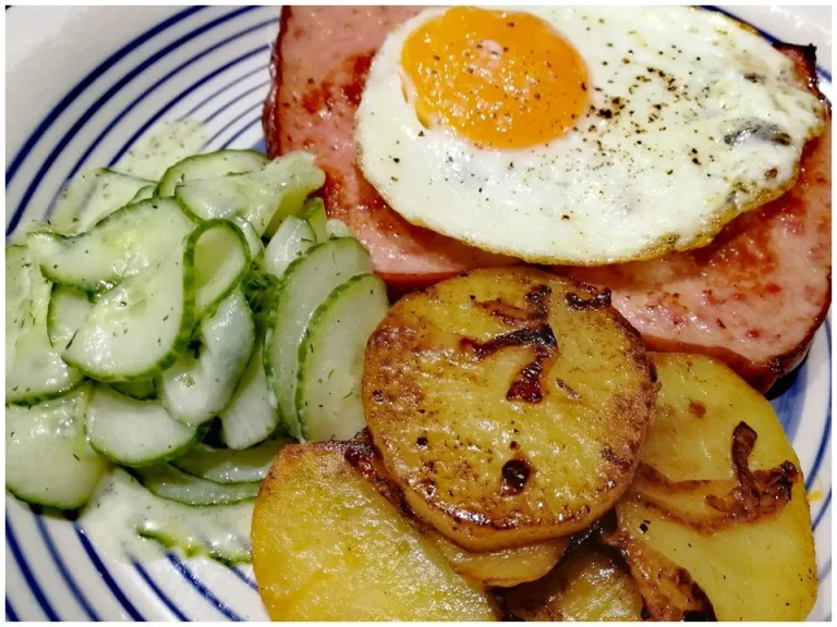 Bratkartoffeln mit Wurst und Spiegelei auf einem Teller serviert