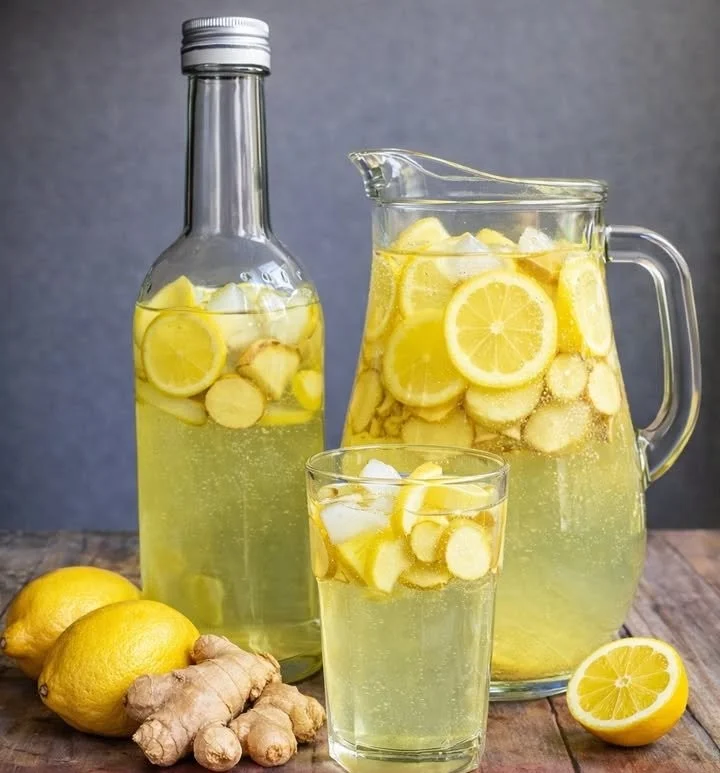 Ein Glas Ingwer Zitronenwasser mit frischen Zitronen und Ingwer.