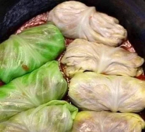 Kohlrouladen mit Fleischfüllung und Gemüse auf einem Teller serviert.