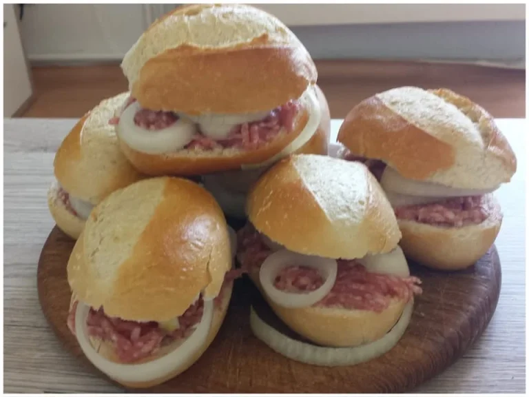 Klassische Mettbrötchen mit Zwiebeln auf einem Holzbrett serviert.
