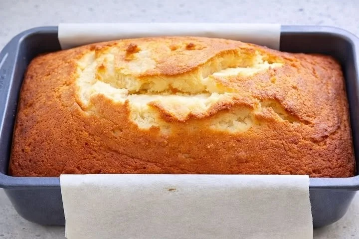Saftiger Quark Rührkuchen auf einem Teller, dekoriert mit Puderzucker.