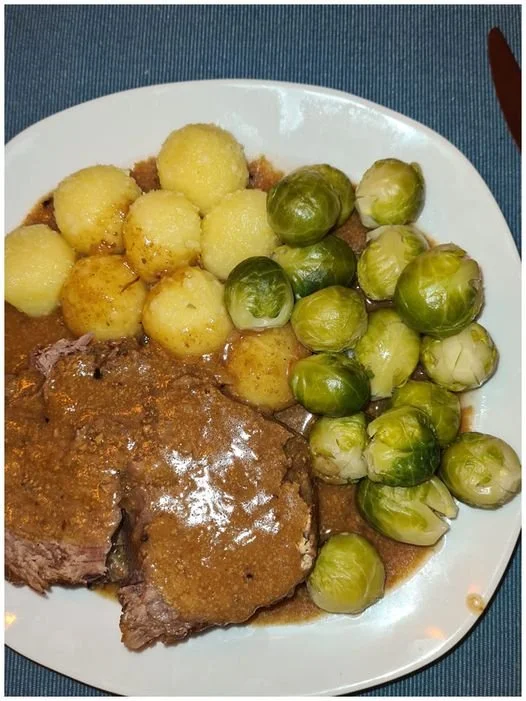 Rinderbraten mit Kartoffelknödeln und Rosenkohl auf einem Teller serviert