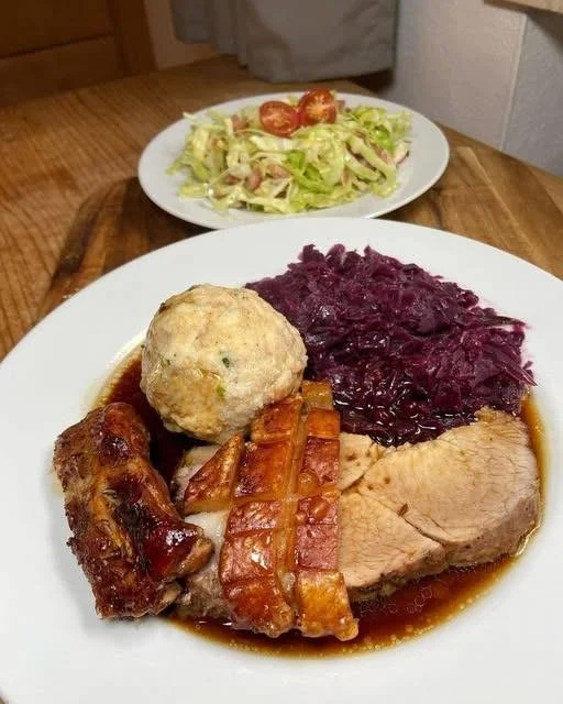 Schweinebraten serviert mit Beilagen auf einem Teller.