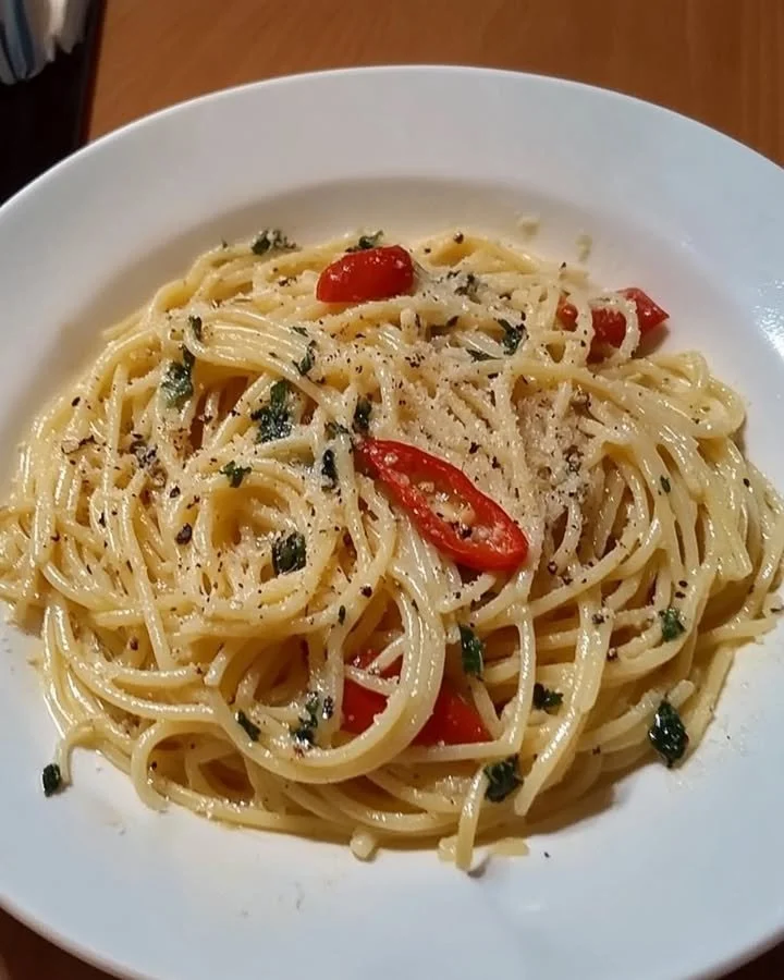 Teller mit Spaghetti Aglio, Olio e Peperoncino, garniert mit frischen Kräutern.