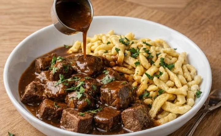 Traditionelles ungarisches Gulasch mit Spätzle auf einem Teller serviert.