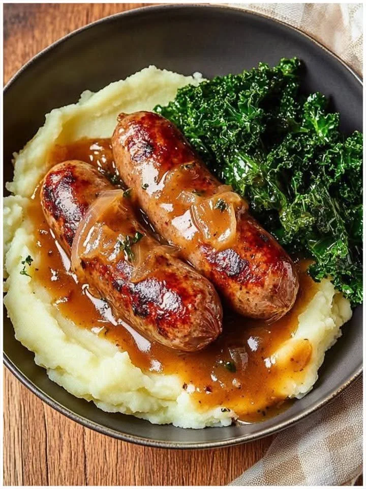 Würstchen mit Kartoffelpüree, Bratensoße und Grünkohl auf einem Teller serviert